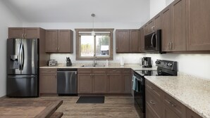 Une cuisine moderne avec des meubles en bois, des appareils en acier inoxydable, une fenêtre et une vue sur l’extérieur.