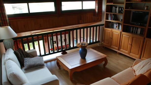 A living room with a wooden railing, a sofa, a coffee table, and a bookshelf.