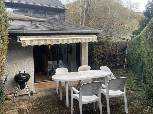 Un patio con mesa y sillas, una parrilla y un espacio cubierto.