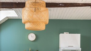 A modern kitchen with white cabinetry, a built-in oven, and a hanging wicker light fixture. - LE PETIT MARIUS - Cocon au cœur du centre-ville historique (Rennes)