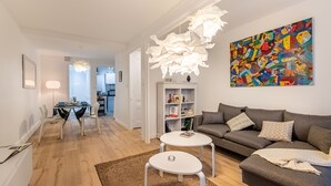 A modern living room with a grey sofa, white coffee table, and a colorful abstract painting. - Isadora - Ravissant T2 au coeur de Lyon (Lyon)