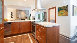 A modern kitchen with wooden cabinets, a stainless steel dishwasher, a built-in oven, and a granite countertop. - Prime Location: 4-Bedroom Chalet Style Home (Whistler)