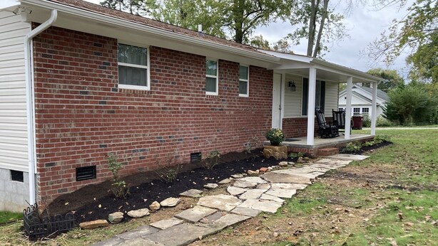 A brick house with a stone pathway leading to a porch.