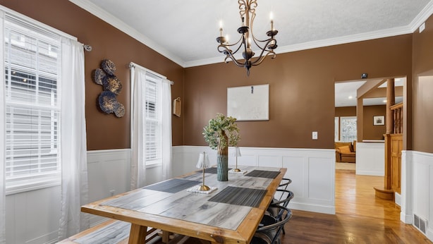 A dining room with a wooden table, benches, and a chandelier.