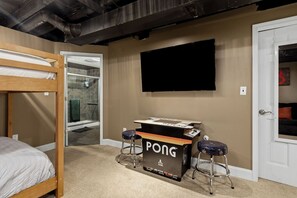 A room with a bunk bed, a ping pong table, and a TV on the wall. - Nest on Vestry: Spacious Historical Home w/ Jacuzzi & Pool Table (Cleveland)