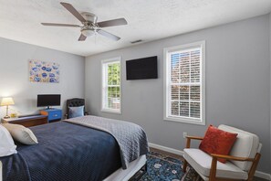 A bedroom with a bed, a chair, a desk with a computer, and a ceiling fan. - Nest on Vestry: Spacious Historical Home w/ Jacuzzi & Pool Table (Cleveland)