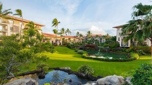 A resort with multiple buildings, a well-maintained lawn, a pond, and palm trees. - Waiohai Beach Club - Island View (Kauai)