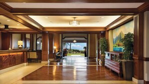 A spacious lobby with a wooden floor, a reception desk, and a large mural of a mountain landscape. - Waiohai Beach Club - Island View (Kauai)