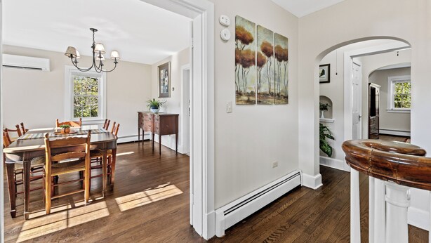 Un coin repas avec une table et des chaises en bois, un lustre et un tableau au mur.