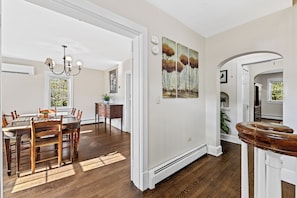 A dining area with a wooden table and chairs, a chandelier, and a painting on the wall.