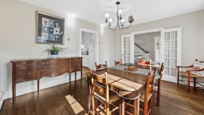 Un coin repas avec une table en bois, des chaises, un lustre et une œuvre d’art encadrée accrochée au mur.