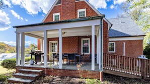 Une maison en briques avec un porche abrité, un espace salon extérieur et un barbecue.