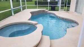 A swimming pool with a hot tub, surrounded by a covered patio area.