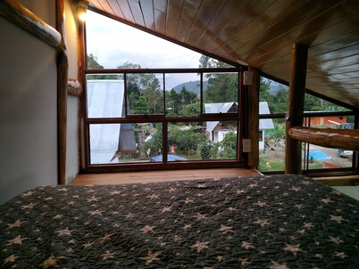 Habitacion tipo cabaña con acabados en madera, terraza con vista hacia la montaña