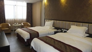 Habitación de hotel con dos camas, un escritorio, una silla y una mesita.