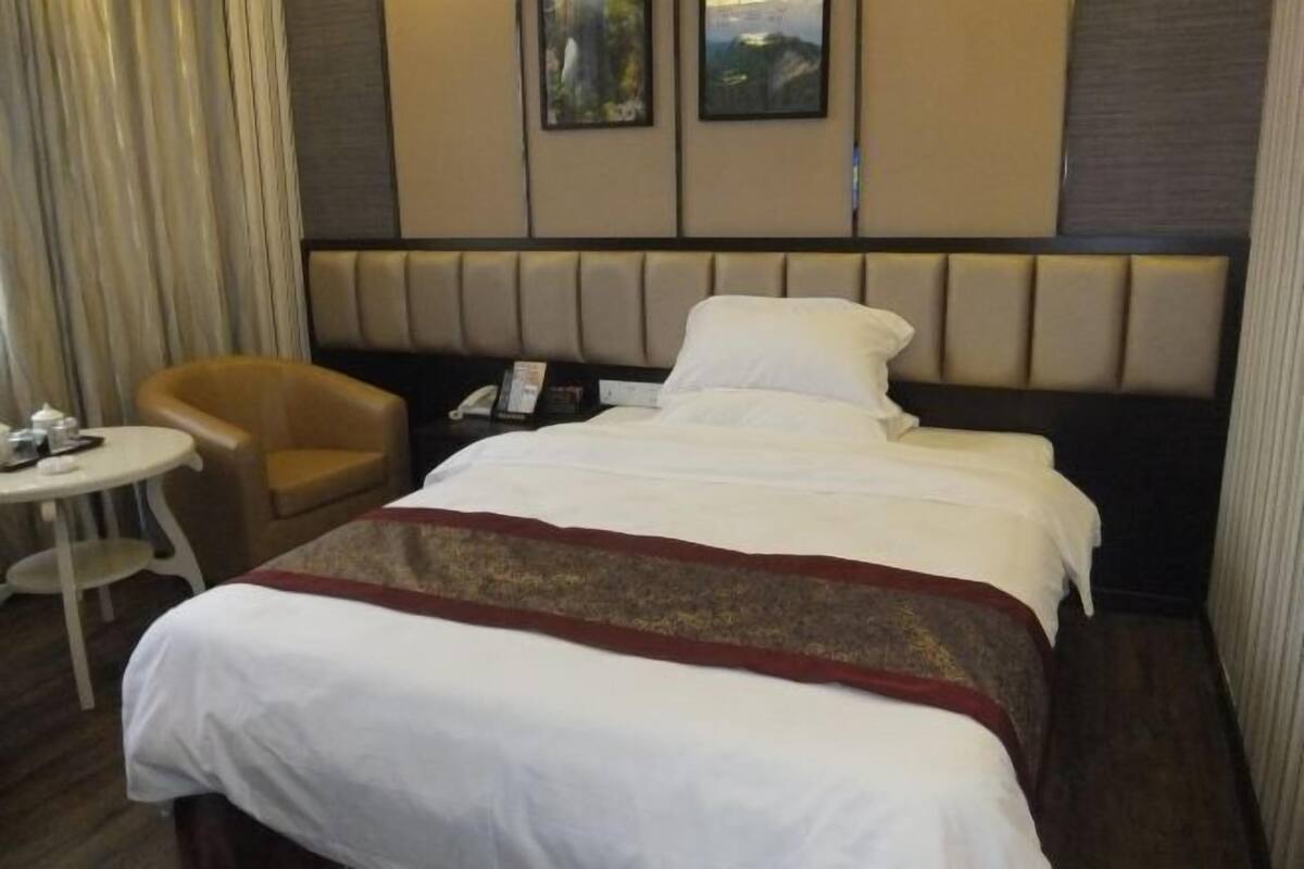 A hotel room with a bed, a chair, a small table, and a telephone.