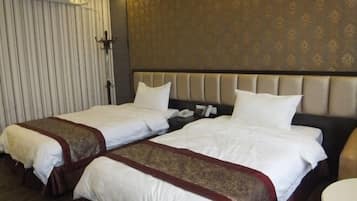 A hotel room with two beds, a headboard, a bedside table, and a wall-mounted air conditioning unit.