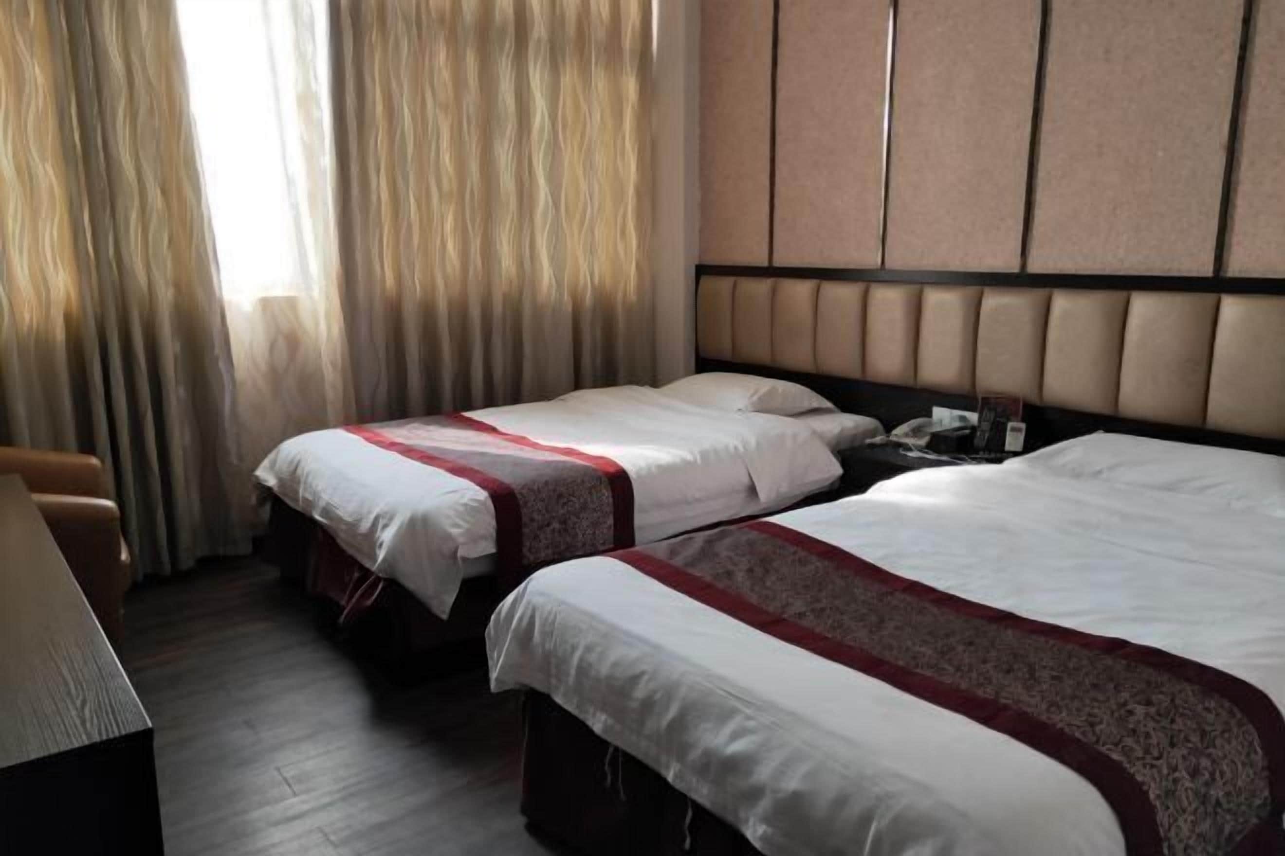 Una camera d'albergo con due letti, una scrivania e una sedia.