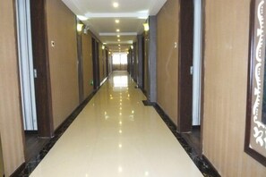 A long, narrow hallway with a reflective floor and wooden paneling on the walls. - Bairun Hotel (Ruyuan)