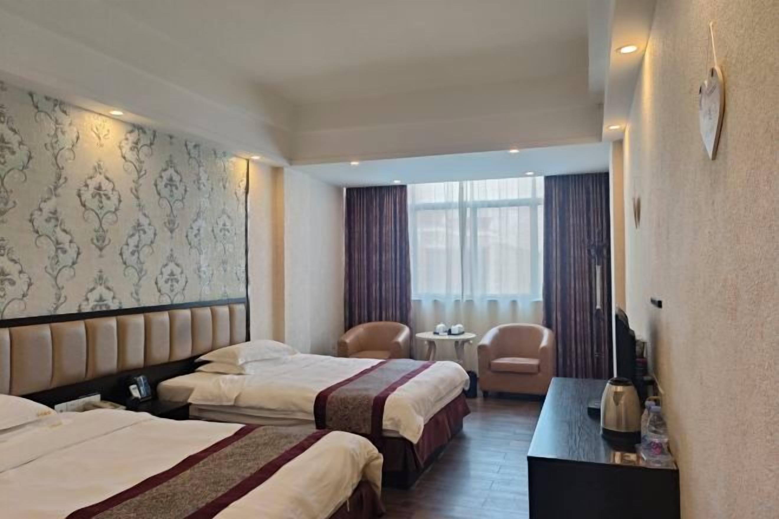 Una camera d'albergo con due letti, una scrivania, una sedia e un tavolino.