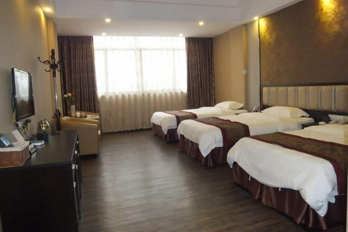 A hotel room with three beds, a desk with a computer, and a television.