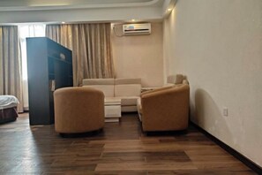 A hotel room with a sofa, two armchairs, a wooden floor, and a wardrobe. - Bairun Hotel (Ruyuan)