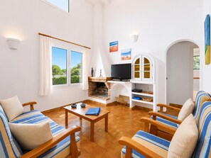 A living room with a fireplace, TV, and seating area. - Eulalia Dos - Three Bedroom Villa, Sleeps 6 (Es Mercadal)