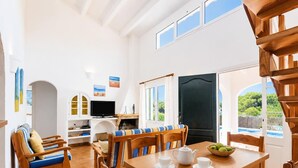Een ruime woonkamer met een houten eettafel, stoelen, een bank en een televisie.