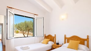 Een hotelkamer met twee bedden, een groot raam met gordijnen, een nachtkastje en een wandlamp.