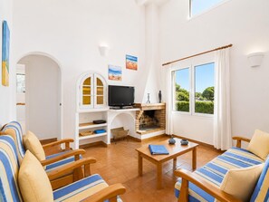 Een woonkamer met een televisie, open haard en zithoek.