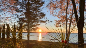 Une vue sur un lac au coucher du soleil, avec des arbres et un hamac.
