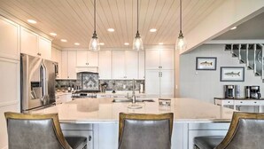 Une cuisine moderne avec des armoires blanches, un grand îlot central et des luminaires suspendus.