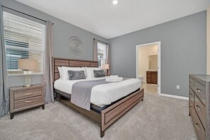 A bedroom with a large bed, two bedside tables, a dresser, and a walk-in closet. - Brand New 7 Bed Villa With Pool & Spa Near Disney (Davenport)