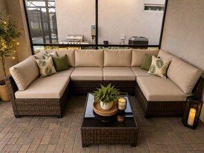 A sectional sofa with cushions, a wicker coffee table with a plant, and a lantern.