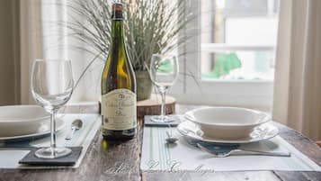 Una botella de sidra ecológica Domaine de la Minotiere Cidre Bouché Bio, dos copas de vino y una mesa de comedor preparada con platos y cubiertos.