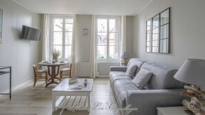 A modern living room with a grey sofa, a coffee table, and a dining area with a table and chairs.