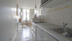A modern kitchen with a stainless steel sink, a dining area with a table and chairs, and a window providing natural light.