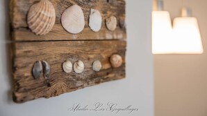 A wooden wall art piece with seashells arranged in two rows.