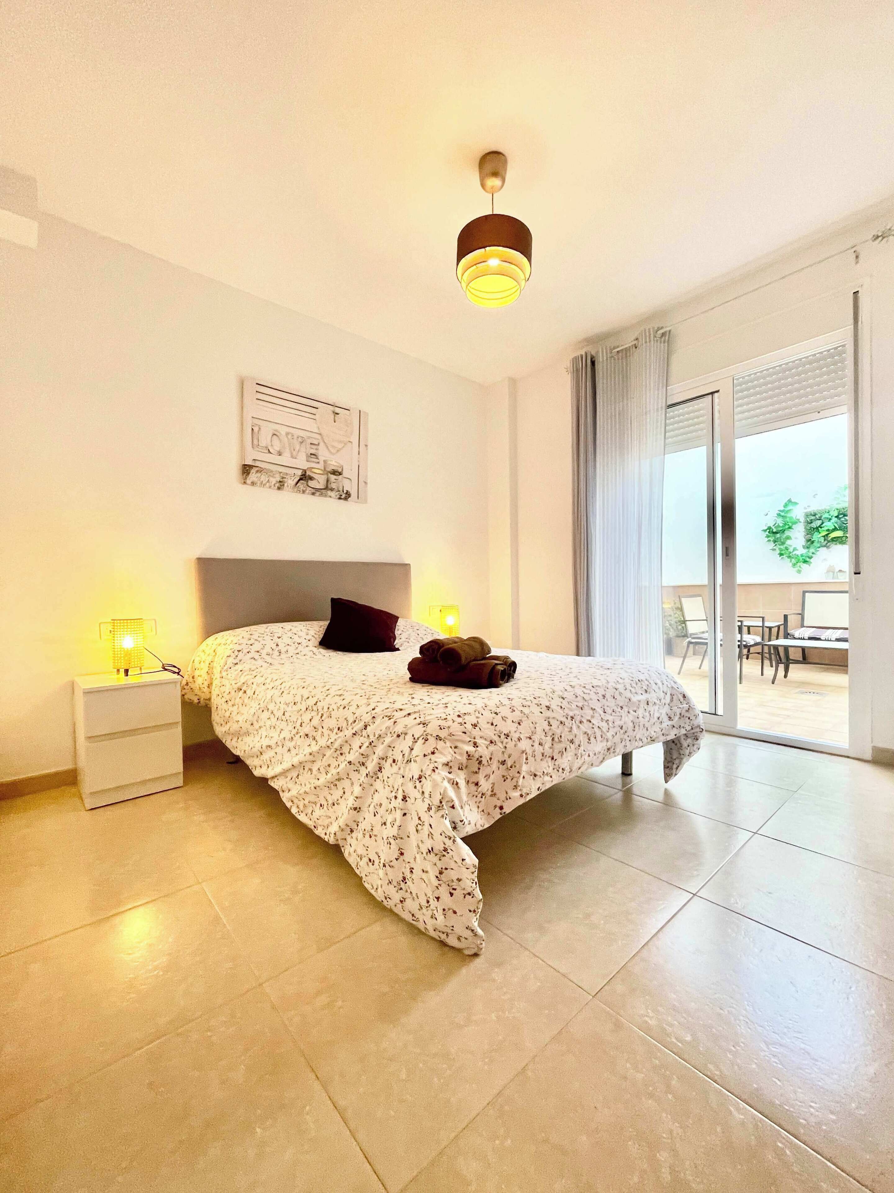 Un dormitorio con cama, mesita de noche y lámpara de techo.