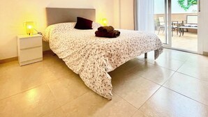 A bedroom with a bed, nightstand, and a ceiling light fixture. - SHR002 Nuevo y Moderno apartamento en Nerja con Patio (Nerja)