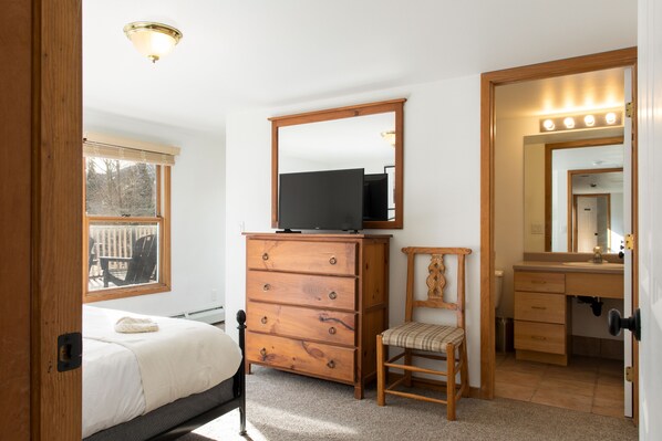 Un dormitorio con cama, cómoda de madera, silla y un espejo grande.