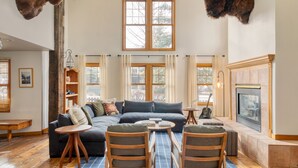 Un salón acogedor con un sofá azul oscuro, sillas de madera, una chimenea y monturas de animales en las paredes.
