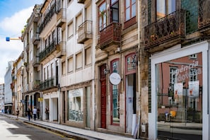 A row of multi-story buildings with balconies, storefronts, and a clear sky.