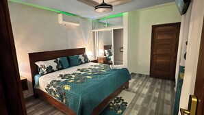 Ein Schlafzimmer mit Bett, Deckenventilator, Kleiderschrank und einer Tür.