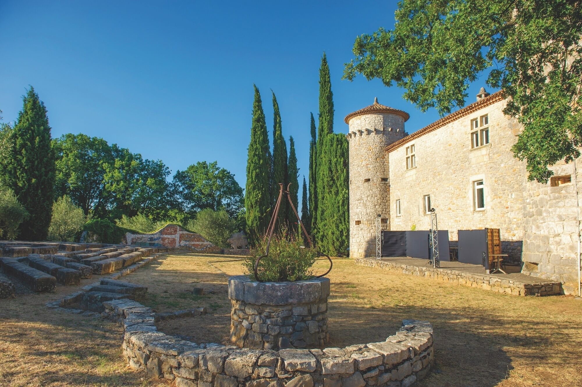 A stone building with a tower, surrounded by trees and a stone pathway.