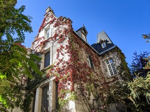 A historic building with ivy-covered walls and a steeply pitched roof. - Bright apartment with a terrace, 7 minutes from Paris (Asnières-sur-Seine)
