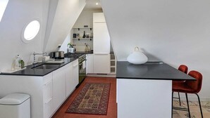 Moderni keittiö, jossa on valkoiset kaapit, musta työtaso ja punainen matto.