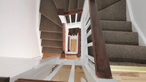 Un escalier avec des rampes en bois et des marches recouvertes de moquette, menant à un palier.