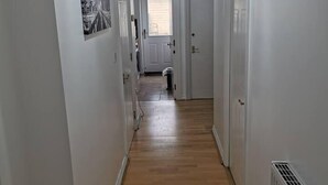 Un couloir étroit avec un plancher en bois, des murs blancs et un ventilateur de plafond.
