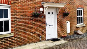 A red brick building with a white door, two windows, and a small porch with a white railing. - Mannys Apartment - Flagship Lodge (Sittingbourne)